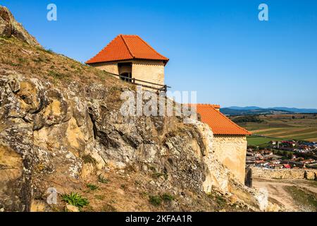 Un primo piano della famosa fortezza medievale di Rupea sulla cima di una collina rocciosa, in Transilvania, Romania, con il paesaggio urbano sullo sfondo Foto Stock