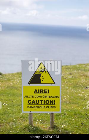 Pittogramma e segno in gaelico e inglese avvertimento di pericolose scogliere, montagna Slieve League, costa atlantica, Contea di Donegal, Irlanda Foto Stock