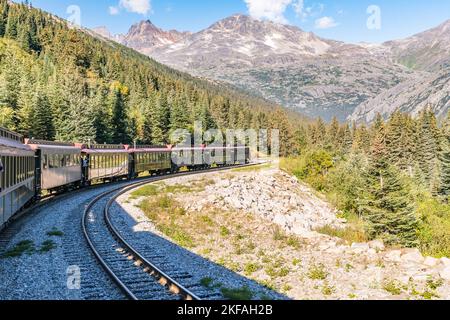 Skagway, AK - 7 settembre 2022: Il treno White Pass e Yukon Route si snoda attraverso le montagne ad est di Skagway. Foto Stock