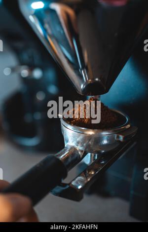 barista con supporto per macinare i chicchi di caffè con macinacaffè professionale Foto Stock