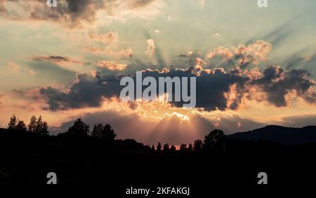 Il cielo nuvoloso sopra la collina silhouette catturato al tramonto Foto Stock