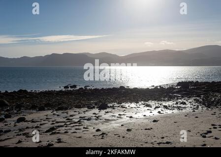 Vista dello stretto di Menai dalla spiaggia tra Beaumaris e Penmon. Una mattina soleggiata e limpida sulla costa di Anglesey, Galles del Nord. Foto Stock