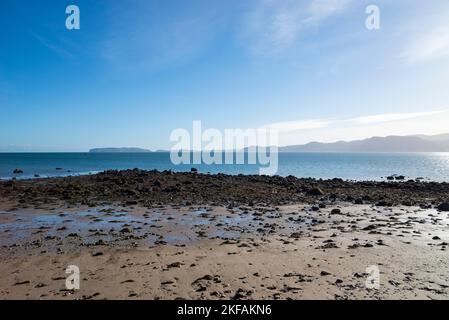 Vista dello stretto di Menai dalla spiaggia tra Beaumaris e Penmon. Una mattina soleggiata e limpida sulla costa di Anglesey, Galles del Nord. Foto Stock