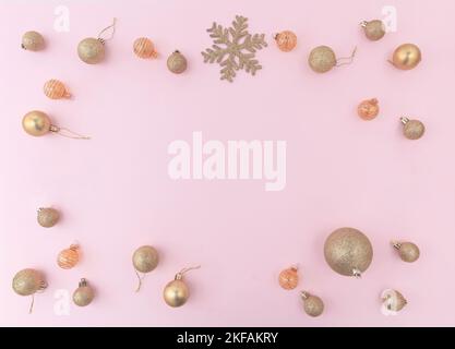 Allegro biglietto di auguri di Natale modello. Cornice baubles oro xmas su sfondo rosa, vista dall'alto. Foto Stock