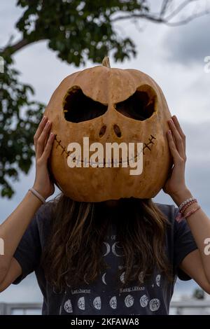 giovane donna con la testa di zucca dopo averla tagliata e averla messa una faccia, halloween, Foto Stock