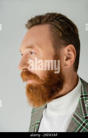 Uomo con beared in giacca a plaid guardando lontano isolato sul grigio Foto Stock