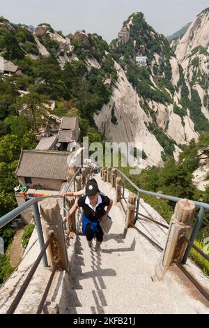 Visitatore / turistico salite ripide scalini tagliati o fissati a una cresta di pietra che conduce verso una cima / una delle cinque vette del monte Huashan / Monte Hua / Monte Hua vicino Huayin, Weinan, Cina, RPC. (125) Foto Stock