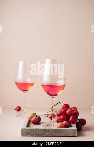 Due bicchieri di vino rosato e un mazzo di uve rosse. Foto Stock