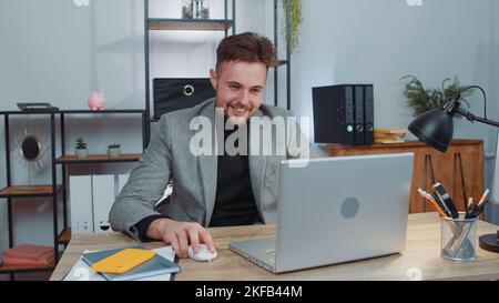 Uomo d'affari freelancer in ufficio, iniziare a lavorare sul computer portatile alla scrivania. Professionista manager freelancer uomo ragazzo lavora su notebook, invia messaggi fare acquisti online guardare film Foto Stock