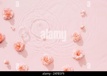 Rosa rose, gocce e onde sulla superficie dell'acqua. Acqua sfondo astratto. Concetto di sfondo per la pubblicità di cosmetici, profumi e spa Foto Stock