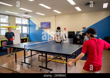 Riku Kato, uno studente del Kadena Language Institute, gioca a ping pong con due adolescenti al Teen Center sulla base aerea di Kadena, Giappone, 1 settembre 2022. Durante il suo tirocinio al Teen Center, Kato incoraggiò la partecipazione a giochi e attività giocando con gli adolescenti durante il suo periodo lì. Kadena Air base,Kadena Language Institute,stagisti,interoperabilità,apprendimento,studenti, Foto Stock
