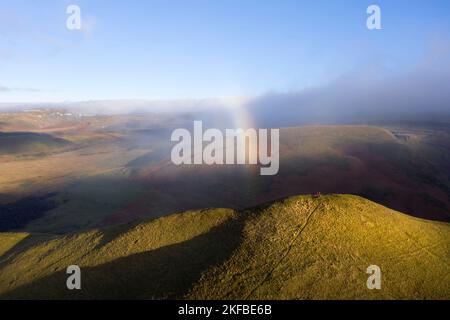 Due camminatori sul Summit Dufton Pike con un arcobaleno sopra di loro, Eden Valley, Cumbria, Regno Unito Foto Stock