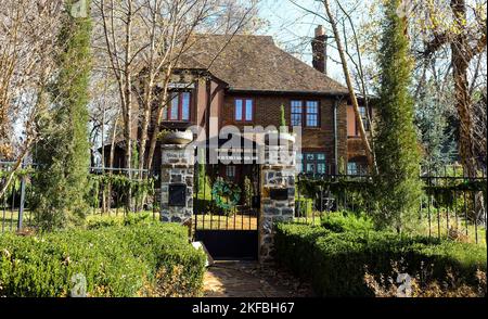 Consegna pacchetto fuori porta di ferro di fronte a lussureggianti case in mattoni a due piani con ghirlande e wreath e luci di Natale Foto Stock