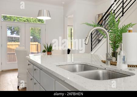 Una bella isola di cucina in pietra bianca nuova di zecca con un rubinetto d'argento e lavandini Foto Stock