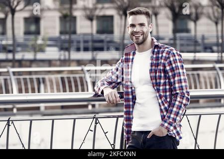 felice sorridente giovane uomo rasato con capelli curati in casual a scacchi camicia outdoor, moda e maschile parrucchiere Foto Stock