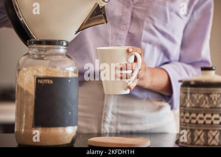 Acqua, bevanda e donna fanno il caffè in cucina per la motivazione, l'energia e la caffeina al mattino. Stile di vita, caffè e primo piano di mani che versano acqua da Foto Stock