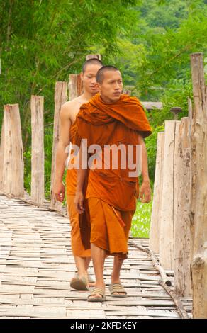 Thailandia: Monaci buddisti che attraversano il ponte di bambù, Wat Phu Sama, su Tong Pae Bamboo Bridge, Mae Hong Son. Il ponte di bambù si estende per 500 metri attraverso il torrente Mae SA Nga e i campi di ricovero. Il ponte permette ai monaci di accedere da Wat Phu lama al piccolo villaggio ad ovest. Foto Stock