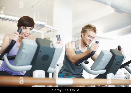 Due persone che usano le cyclette in palestra. Foto Stock