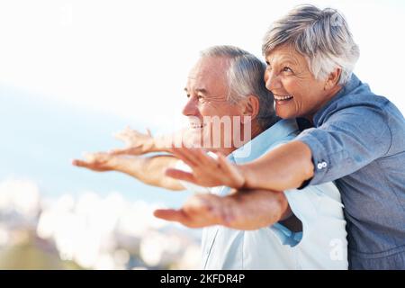 Coppia godendo anni d'oro. Coppia matura allegra sorridente mentre si gode all'aperto con le braccia distese. Foto Stock