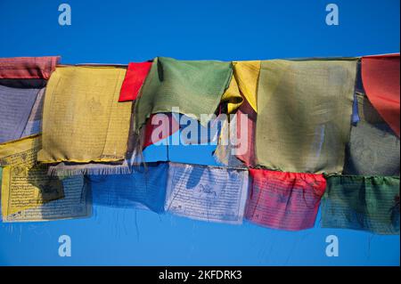 Colorate bandiere di preghiera buddiste che sventolano nel vento sulle montagne dell'Himalaya, Nepal Foto Stock