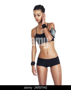 In attesa di un perfetto allenamento. Studio di una giovane donna in forma sportiva che ascolta musica isolata sul bianco. Foto Stock