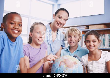 Amiamo la terra. Un insegnante di geografia piuttosto giovane che insegna ai suoi studenti il mondo usando un globo di terra. Foto Stock