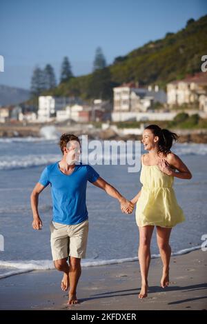 Bagnate i piedi, una coppia affettuosa che cammina sulla spiaggia. Foto Stock