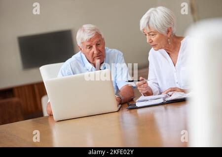 È che il totale finale. Una coppia anziana che passa sopra un certo lavoro di ufficio mentre usando un laptop. Foto Stock