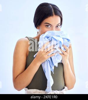 Fresco, lavanderia e donna che odorano vestiti puliti con un sorriso, pace e calma in mockup studio sfondo. Profumo, pulito e odore femminile di abbigliamento aroma Foto Stock