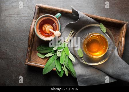 Salvia il tè in una tazza con miele servito in un primo piano trey Foto Stock