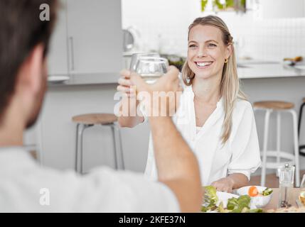 Coppia, brindisi e pranzo per una data romantica nella casa di famiglia mentre si rilassa con amore e cura. Anniversario, pasto e saluti con un uomo e una donna Foto Stock