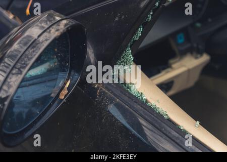 Primo piano dello specchio laterale di un'auto nera e vetro del finestrino rotto. Concetto di incidente e incidente del veicolo. Finestra sinistra. Foto di alta qualità Foto Stock