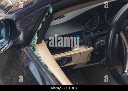 Concetto di violazione del diritto penale. Rottura del vetro del finestrino lato conducente in un'auto. Pezzi di vetro blu turchese frantumati. Furto di automobili. Foto di alta qualità Foto Stock
