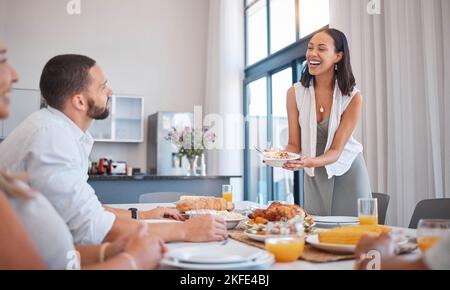 Famiglia, amici e donne che servono il pranzo per festeggiare Natale, compleanno o fine settimana. Famiglia felice, uomini e donne sorridono al tavolo mangiare e. Foto Stock
