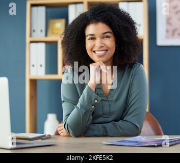 Faccia, risorse felici e umane con una donna nera di affari seduta ad una scrivania nel suo ufficio. Ritratto, sorriso e intervista con una donna manager hr Foto Stock