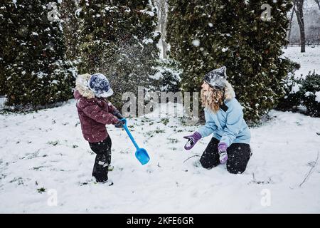 Famiglia felice, madre e figlio che si divertono all'aperto in inverno neve sfondo natura. Mamma e bambino giocano a palla di neve nel parco invernale all'aperto Foto Stock