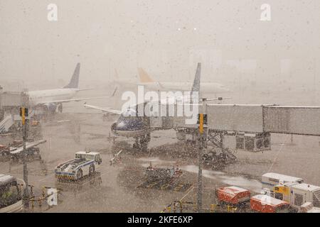 Affollata vista dell'aeroporto con aeroplani e veicoli di servizio nelle giornate invernali innevate Foto Stock