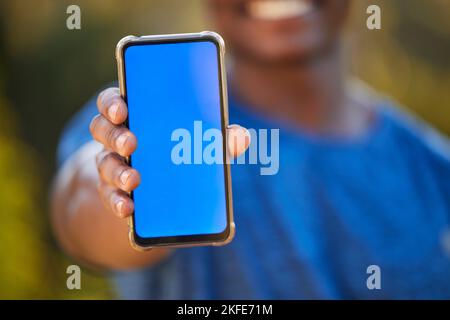 Telefono, mockup e schermo blu in mano di un uomo nero all'aperto per l'esercizio fisico o il monitoraggio del fitness. Marketing, pubblicità e schermo verde con un maschio Foto Stock