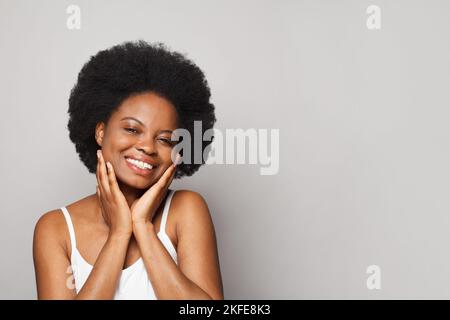 Primo piano ritratto di bella donna splendida toccare guance con delizia sulla pelle liscia su sfondo bianco Foto Stock