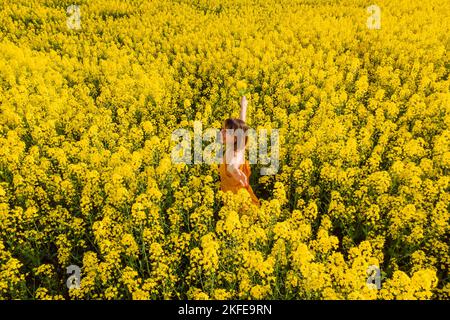 Donna in fiore campo di colza. Fiori gialli e donna felice Foto Stock