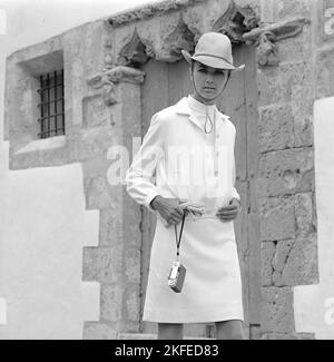 Fashion shoot sull'isola spagnola Ibiza negli anni '1960s. Un modello di moda nella moda decennale. Un abito bianco e un cappello.1967 Foto Stock