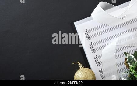 Choral christmas music performance concept background con Binder con spartiti e decorazione natalizia su tavolo nero. Vista dall'alto. Foto Stock