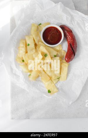 Fettine di yam fritto, salsiccia e salsa, fettine di yam fritto e stufato su carta da pergamena, patatine fritte nigeriane Foto Stock