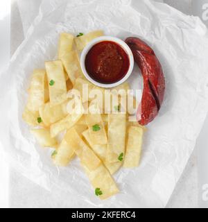 Fettine di yam fritto, salsiccia e salsa, fettine di yam fritto e stufato su carta da pergamena, patatine fritte nigeriane Foto Stock