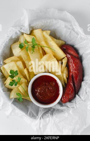 Fettine di yam fritto, salsiccia e salsa, fettine di yam fritto e stufato su carta da pergamena, patatine fritte nigeriane Foto Stock