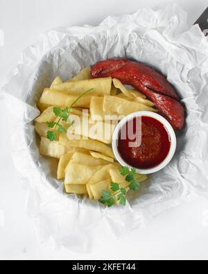 Fettine di yam fritto, salsiccia e salsa, fettine di yam fritto e stufato su carta da pergamena, patatine fritte nigeriane Foto Stock