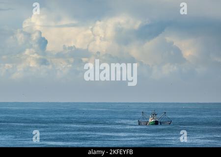 Un taglierino con reti di trascinamento sollevate sulle acque blu del mare del Nord con nuvole soleggiate Foto Stock