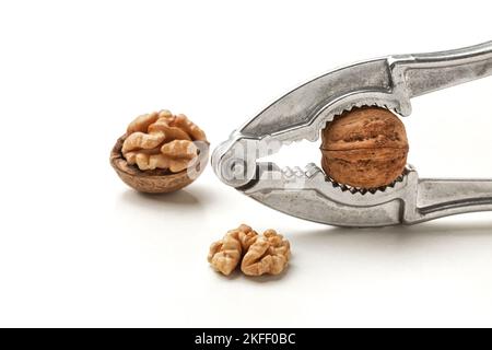 schiaccianoci con noci chiuse e fessurate su sfondo bianco. dado Foto Stock