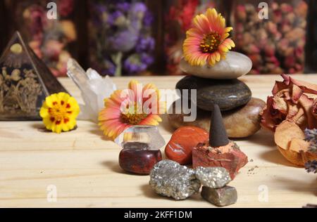 Cono di incenso su lastra di pietra con cristalli di Chakra e fiori Foto Stock