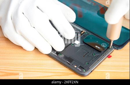 Immagine di un tecnico che si avvita sul retro di un telefono cellulare Foto Stock